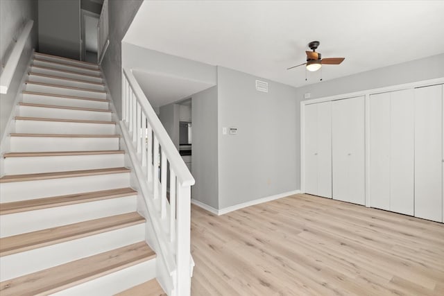 stairway with hardwood / wood-style floors and ceiling fan