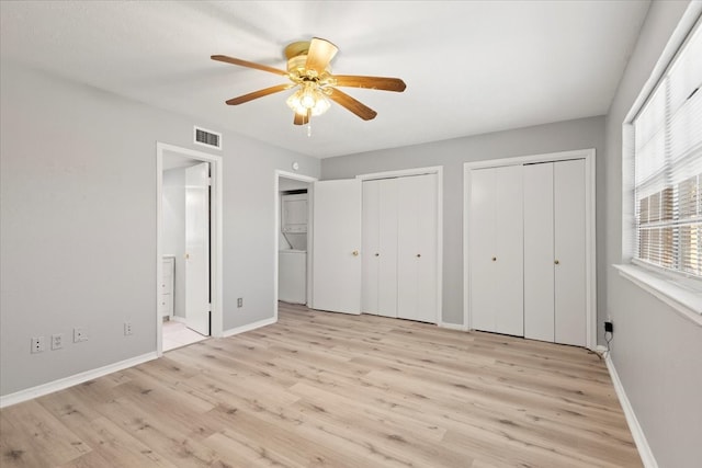 unfurnished bedroom with light wood-type flooring, two closets, and ceiling fan