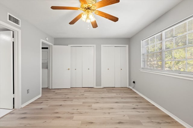 unfurnished bedroom featuring ceiling fan, light hardwood / wood-style floors, and two closets