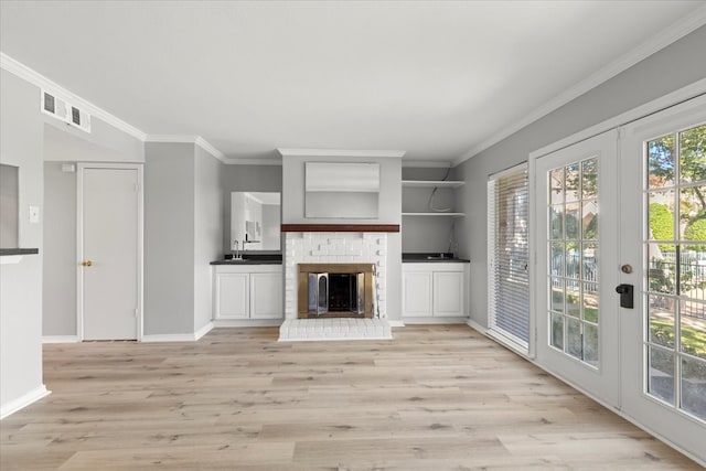 unfurnished living room featuring a fireplace, french doors, light wood-type flooring, and ornamental molding