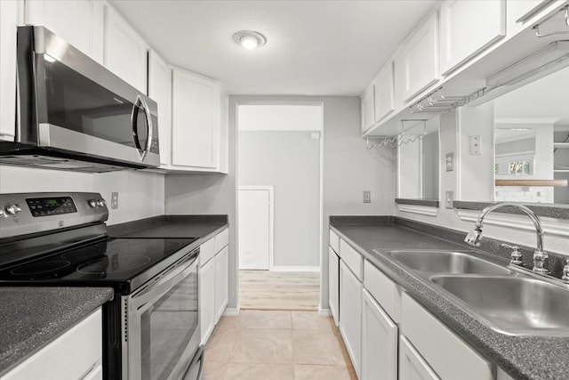 kitchen with sink, white cabinets, stainless steel appliances, and light tile patterned floors