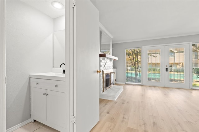 interior space with vanity, french doors, crown molding, a fireplace, and wood-type flooring