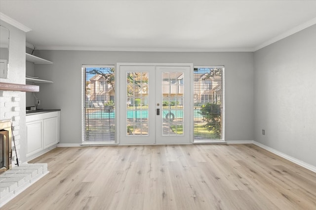 entryway featuring light wood-type flooring, a brick fireplace, and ornamental molding