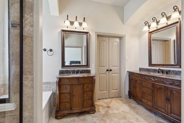 full bath featuring tile patterned flooring, two vanities, a sink, and a garden tub