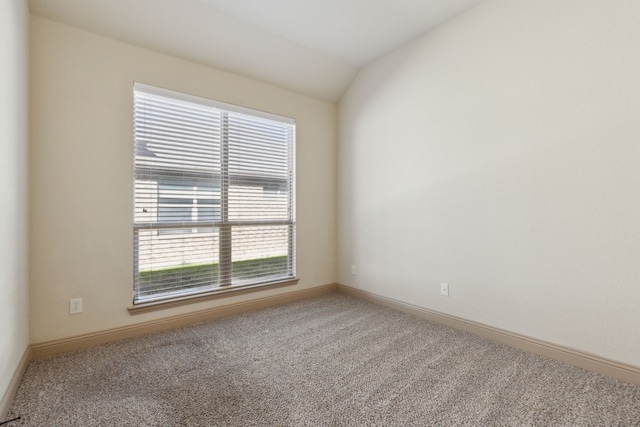 empty room with lofted ceiling, carpet flooring, and baseboards