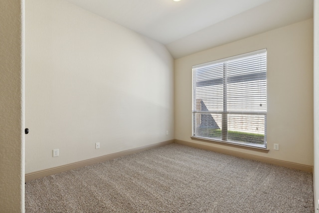 carpeted spare room featuring vaulted ceiling and baseboards