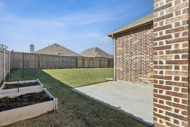 view of yard featuring a garden, a fenced backyard, and a patio