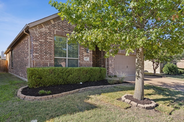 view of front of house with an attached garage, a front yard, and brick siding