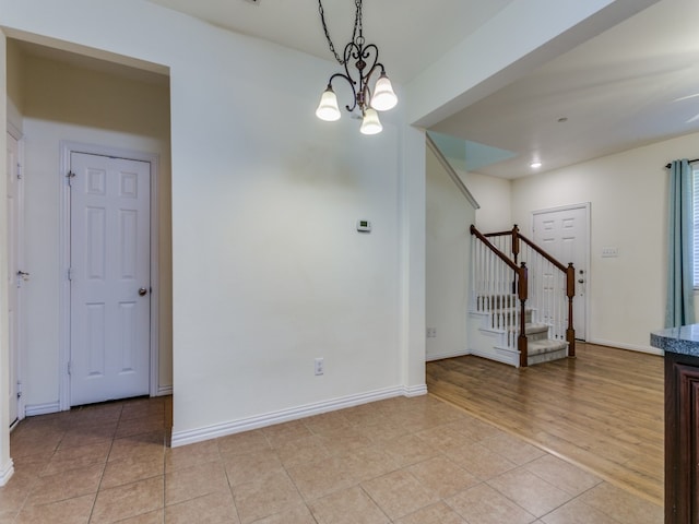 spare room with light hardwood / wood-style floors and a notable chandelier