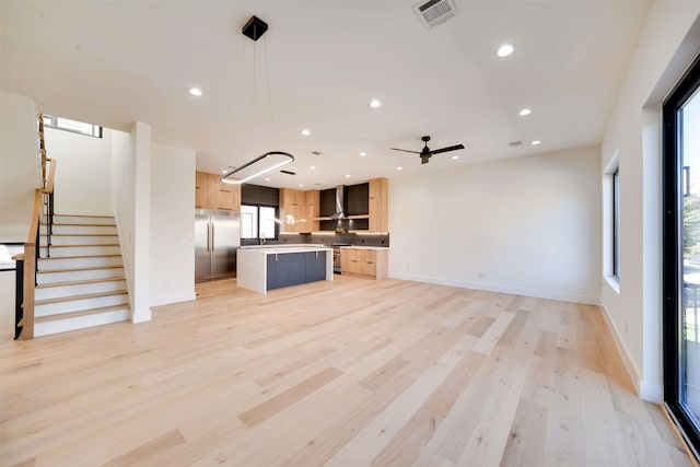 unfurnished living room featuring light hardwood / wood-style floors, ceiling fan, and sink