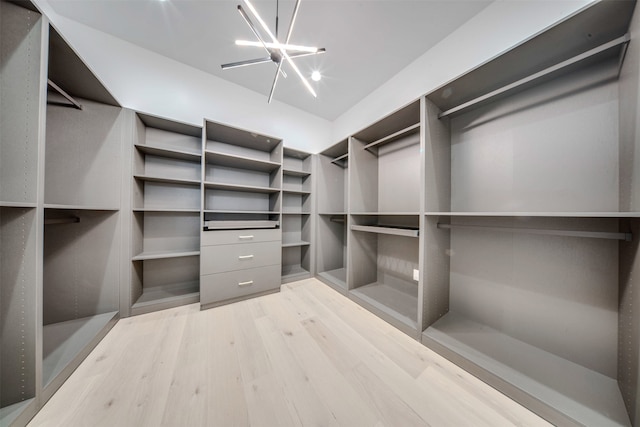 walk in closet featuring a notable chandelier and light hardwood / wood-style flooring