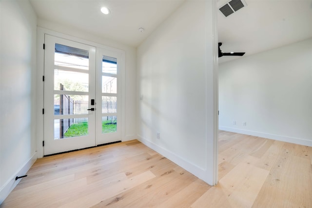 entryway with a healthy amount of sunlight, light wood-type flooring, french doors, and vaulted ceiling