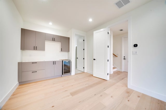 kitchen with gray cabinets, light wood-type flooring, and wine cooler