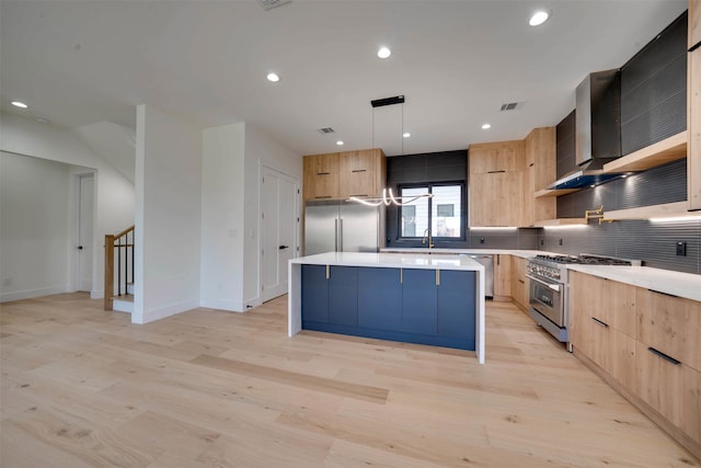 kitchen with sink, premium appliances, light hardwood / wood-style flooring, pendant lighting, and a kitchen island