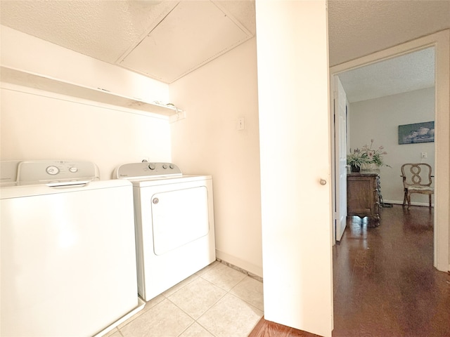 laundry room featuring separate washer and dryer, a textured ceiling, and light tile patterned floors