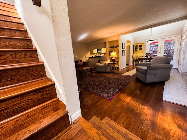 stairs featuring hardwood / wood-style floors, a textured ceiling, and french doors