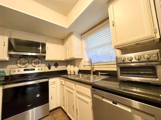 kitchen with white cabinets, appliances with stainless steel finishes, tile patterned floors, and sink