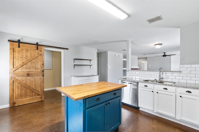 kitchen with white cabinets, sink, stainless steel dishwasher, a barn door, and blue cabinetry