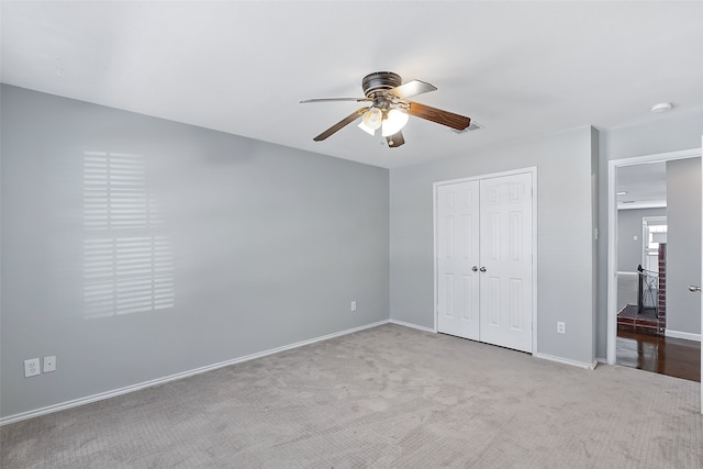 unfurnished bedroom featuring a closet, light colored carpet, and ceiling fan