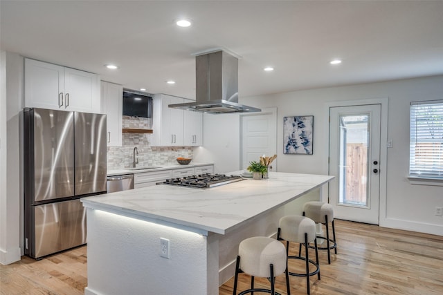 kitchen featuring a kitchen island, island range hood, sink, white cabinets, and stainless steel appliances