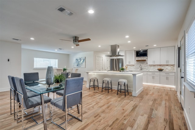 dining area featuring ceiling fan, sink, and light hardwood / wood-style floors