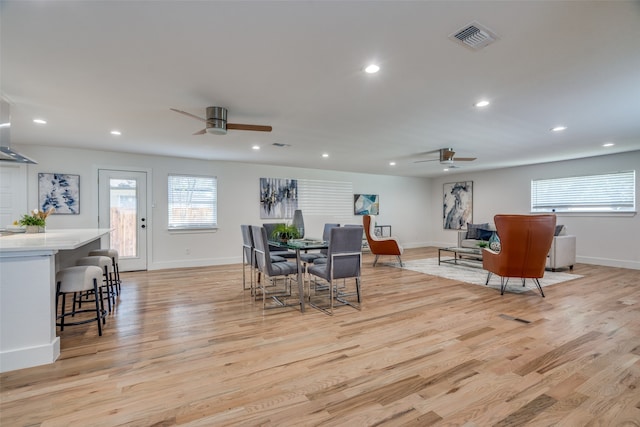 dining space with ceiling fan and light wood-type flooring