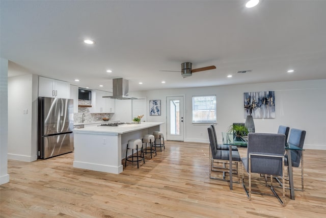 kitchen with a kitchen island, appliances with stainless steel finishes, island range hood, a breakfast bar area, and white cabinets