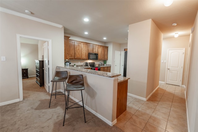 kitchen with light stone countertops, electric range, kitchen peninsula, a kitchen bar, and light carpet