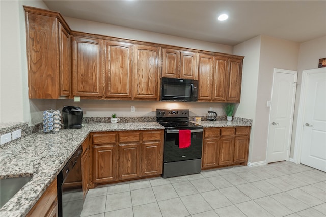 kitchen featuring light stone countertops, light tile patterned floors, and black appliances