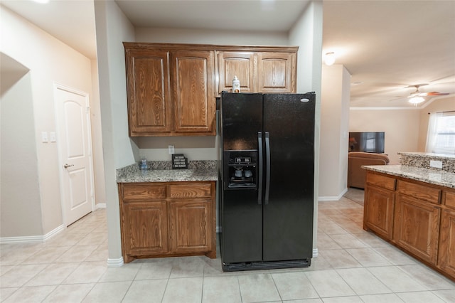 kitchen with black fridge, light tile patterned floors, light stone countertops, and ceiling fan