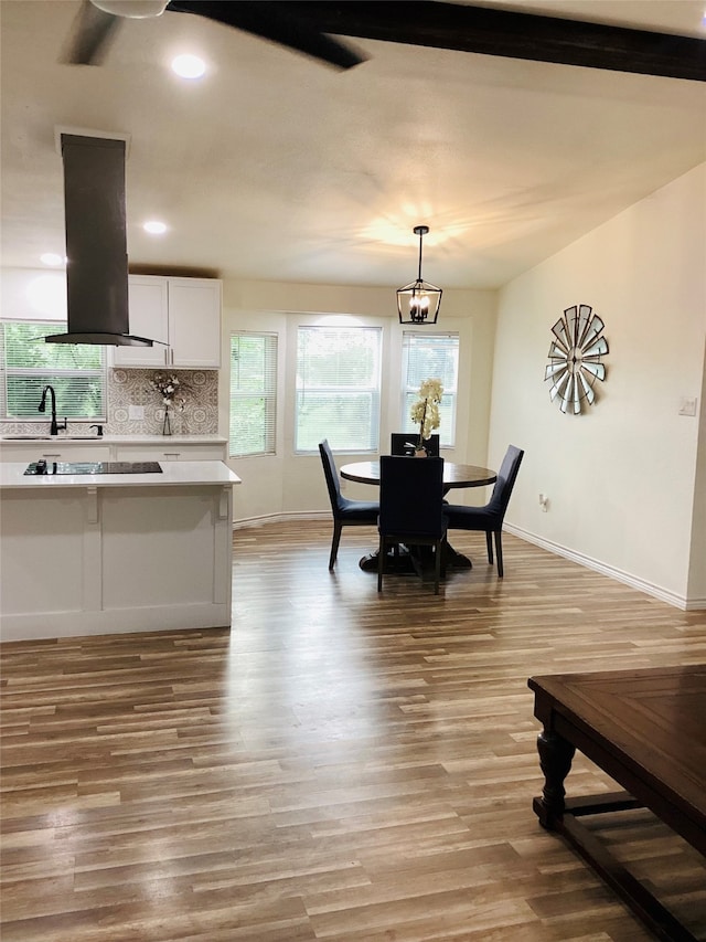 dining space with sink, light hardwood / wood-style flooring, and an inviting chandelier