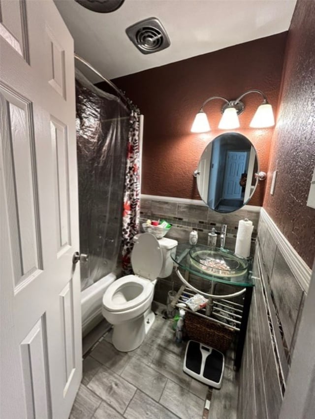 full bathroom with shower / bath combination with curtain, toilet, tile walls, and vanity