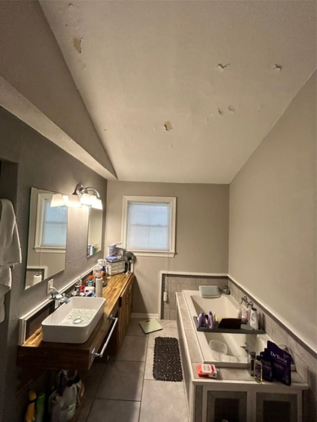 bathroom with tile patterned floors, vanity, a bath, and lofted ceiling