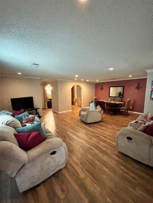 living room with ornamental molding, a textured ceiling, and hardwood / wood-style flooring