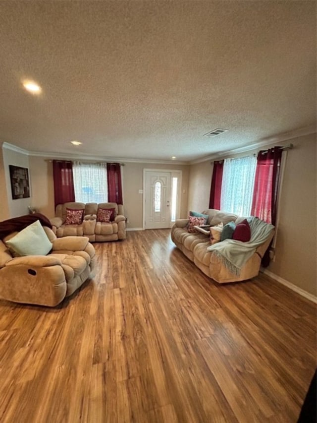 living room with a textured ceiling, hardwood / wood-style flooring, and crown molding