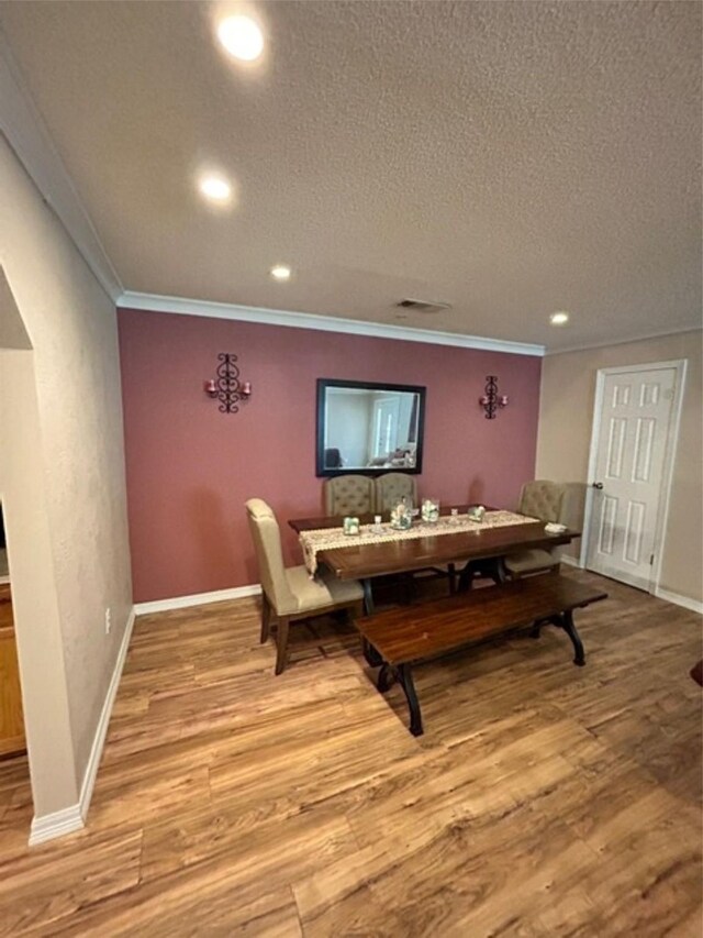 dining space featuring a textured ceiling, light hardwood / wood-style floors, and crown molding