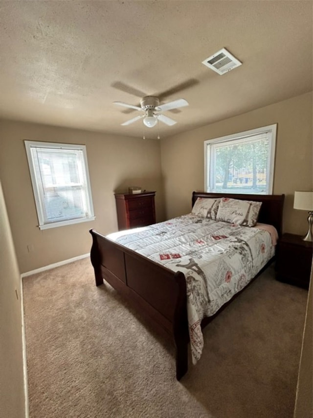 carpeted bedroom featuring a textured ceiling, multiple windows, and ceiling fan