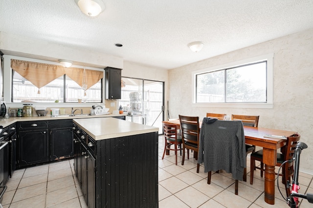 kitchen with a kitchen island, a textured ceiling, light countertops, and dark cabinets