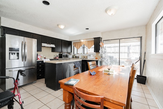 kitchen featuring a center island, light tile patterned flooring, stainless steel appliances, and a textured ceiling