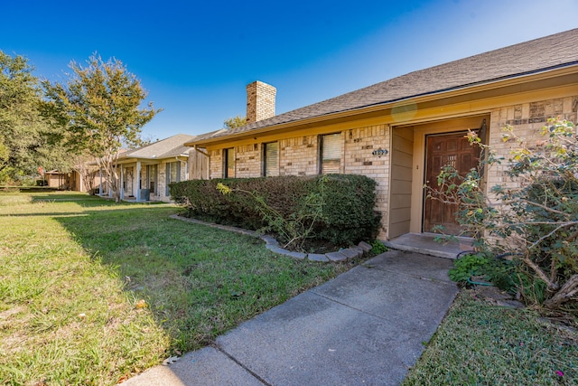 doorway to property with a lawn, brick siding, and a chimney