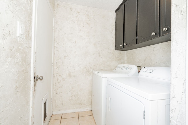 laundry room with light tile patterned floors, cabinet space, baseboards, and washing machine and clothes dryer