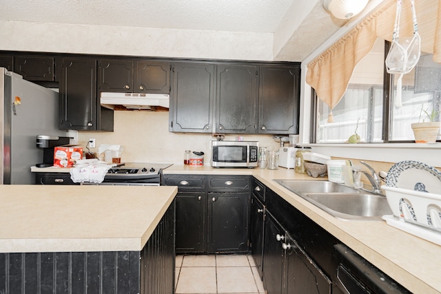 kitchen with light tile patterned floors, a sink, light countertops, appliances with stainless steel finishes, and under cabinet range hood