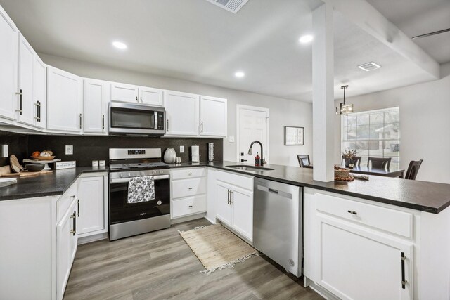 kitchen with kitchen peninsula, white cabinetry, sink, and appliances with stainless steel finishes