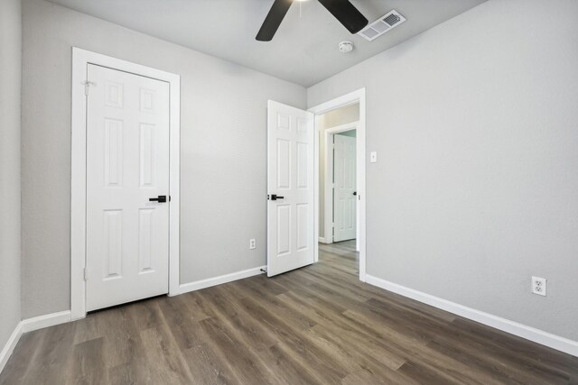 unfurnished bedroom featuring a closet, ceiling fan, and dark hardwood / wood-style flooring