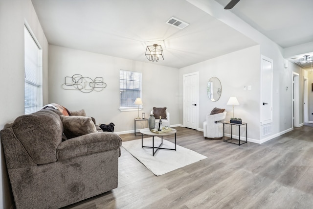 living room with hardwood / wood-style flooring and ceiling fan with notable chandelier