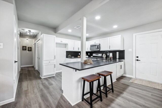 kitchen featuring sink, tasteful backsplash, light hardwood / wood-style flooring, white cabinets, and appliances with stainless steel finishes