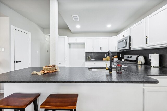 kitchen featuring white cabinets, kitchen peninsula, stainless steel appliances, and a breakfast bar area