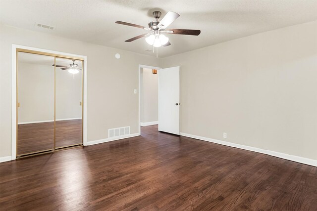 unfurnished bedroom featuring ceiling fan, a closet, dark wood-type flooring, and a textured ceiling