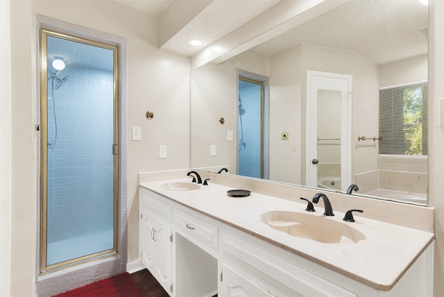 bathroom featuring plus walk in shower, vanity, and a textured ceiling