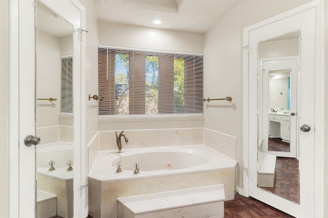 bathroom featuring parquet flooring, a bath, and a textured ceiling